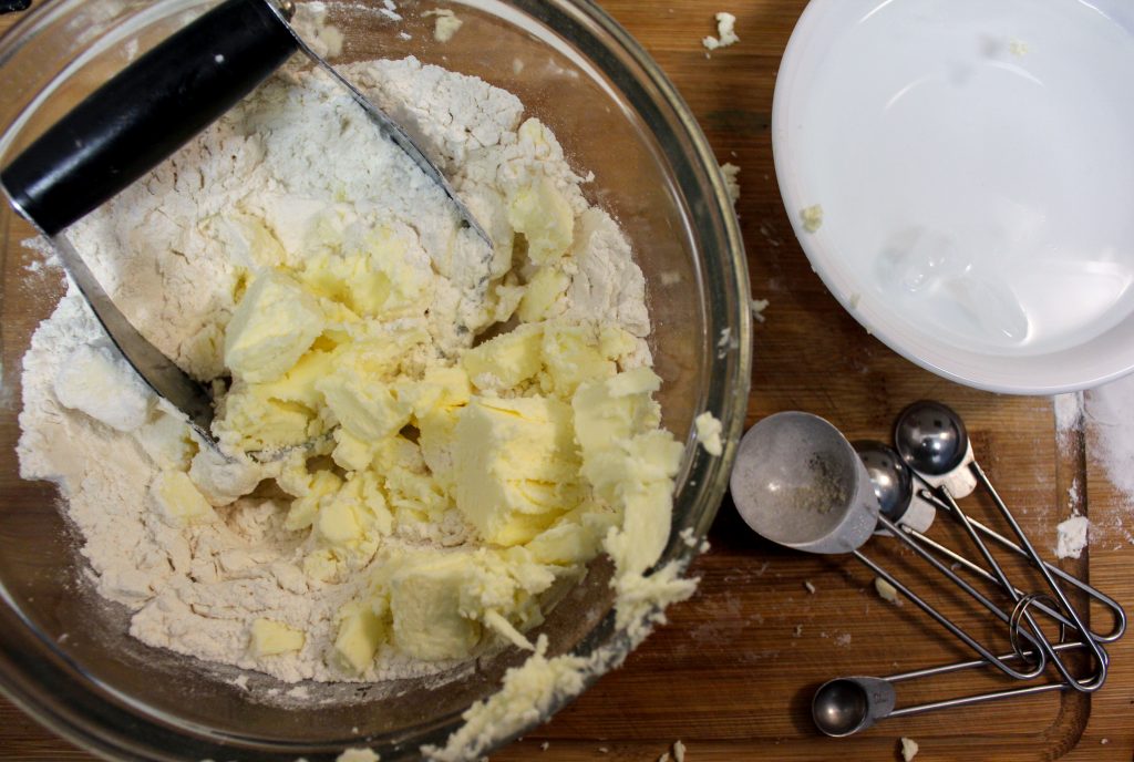 glass bowl of flour and butter on acutting board