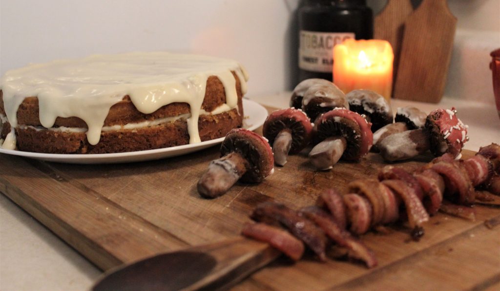 cinnamon bacon swirl cake, candied bacon, and gingerbread mushrooms on a wooden cutting board 